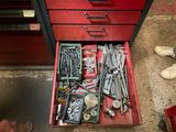 un tiroir rempli d'outils posé par terre à côté d'une paire de chaussures