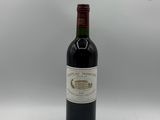 une bouteille de vin rouge posée sur une table blanche, sur fond gris