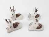 trois cerfs blancs aux bois bruns sont couchés sur une surface blanche