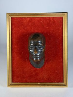 une image représentant une tête d'homme en bronze dans un cadre doré