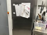 a stainless steel refrigerator in a kitchen with a lot of clutter on the door