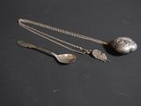 deux cuillères en argent et une boule en argent posées sur un fond noir