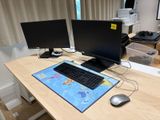 deux écrans d'ordinateur posés sur un bureau, avec une souris et un clavier