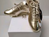 gold and black soccer shoes on top of a white box