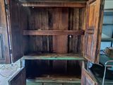 une armoire en bois dont la porte est ouverte, dans une pièce
