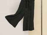 un pantalon noir suspendu à un portant devant un mur blanc