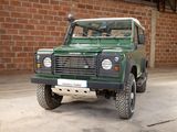 a green land rover parked in front of a brick wall