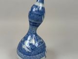 un vase bleu et blanc en forme de calebasse posé sur un fond blanc