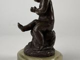 statue of a boy sitting on a rock with his hands on his knees