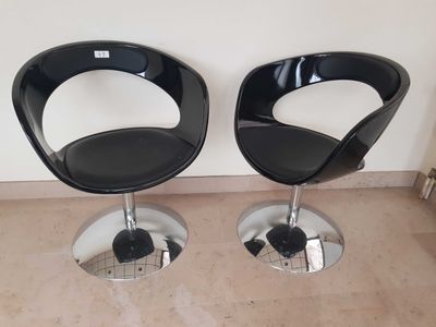 pair of black leather chairs with chrome bases and chrome feet