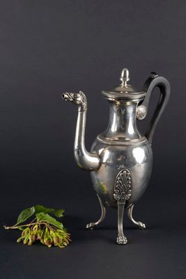 une théière ancienne en argent ornée d'une fleur sur fond noir