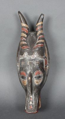 une image représentant un masque en bois muni de cornes sur fond gris