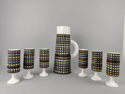 cinq verres et un pichet posés sur une table