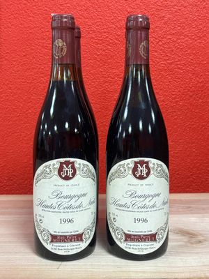 two bottles of red wine sitting on top of a wooden table