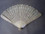 a white lace fan on a table with a tag on it