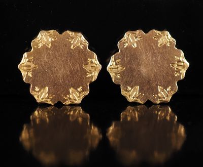une paire de boucles d'oreilles en or sur une surface noire