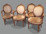four antique chairs with upholstered arms and a cane back