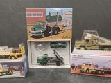 Plusieurs camions miniatures sont rangés dans des boîtes posées sur une table