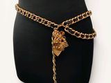 the gold chain belt has a heart charm attached to it