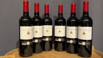 six bottles of red wine are lined up on a wooden barrel