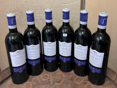 six bouteilles de vin rouge sont alignées sur un tonneau