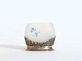 un petit vase blanc orné d'une fleur bleue