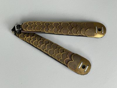 une paire de couteaux de poche vintage plaqués laiton posés sur une surface blanche