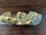 a gold statue of a woman laying on a rock