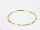 gros plan d'un bracelet en or sur une surface blanche