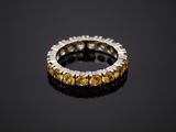 a close up of a yellow sapphire and diamond ring on a black surface