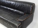 a black leather couch that is sitting on a white floor