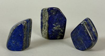 three pieces of lapis stone on a white surface