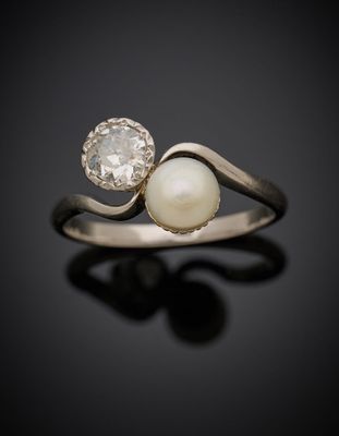 une bague en perles blanches et diamants sur une surface noire