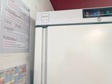 a white refrigerator in a room with a red wall