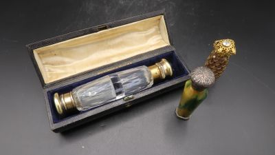 une petite bouteille en verre avec une poignée dorée, dans une boîte