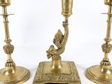 three brass candlesticks with a bird on top of them