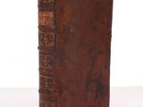 un vieux livre à la couverture marron posé sur une table blanche