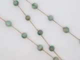 un gros plan d'un collier composé de perles vertes sur un fond blanc