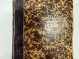un vieux livre à la couverture brune posé sur une surface blanche