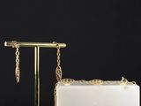 a white and gold purse with a chain hanging from it