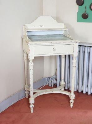 un bureau blanc sur lequel est posé un miroir, dans une pièce équipée d'un radiateur