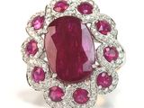 a close up of a ruby and diamond ring on a white surface