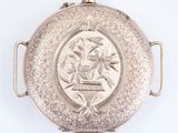 an antique silver pocket watch on a white background with a bird on it