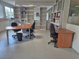 a room with a desk, chairs, and a book shelf