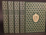 trois livres verts ornés de motifs dorés, posés sur une table