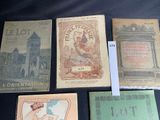 several old books sitting on a table with a black background