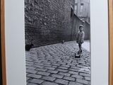 black and white photograph of a boy on a skateboard on a cobblestone street