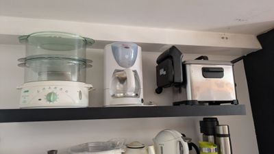 une étagère de cuisine sur laquelle se trouvent un mixeur, une cafetière et d'autres ustensiles de cuisine