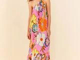 a woman in a pink floral dress standing in front of a white background