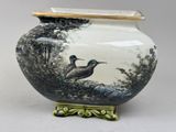 a vase with a bird on it sitting on a table